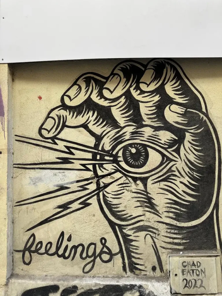Mural en blanco y negro con una mano sujetando un ojo y la palabra feelings en una pared de Málaga