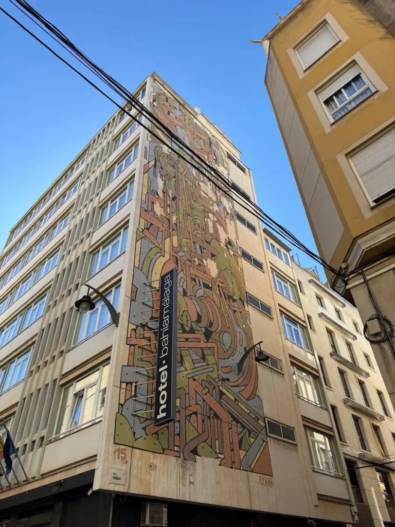 Gran mural de formas geométricas y tonos terrosos en la fachada del Hotel Bahía Málaga