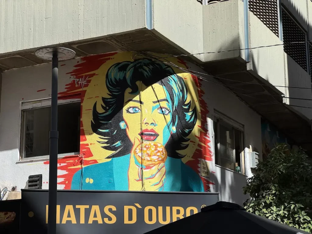 Mural colorido de una mujer con estilo pop art sosteniendo un donut en una calle de Málaga